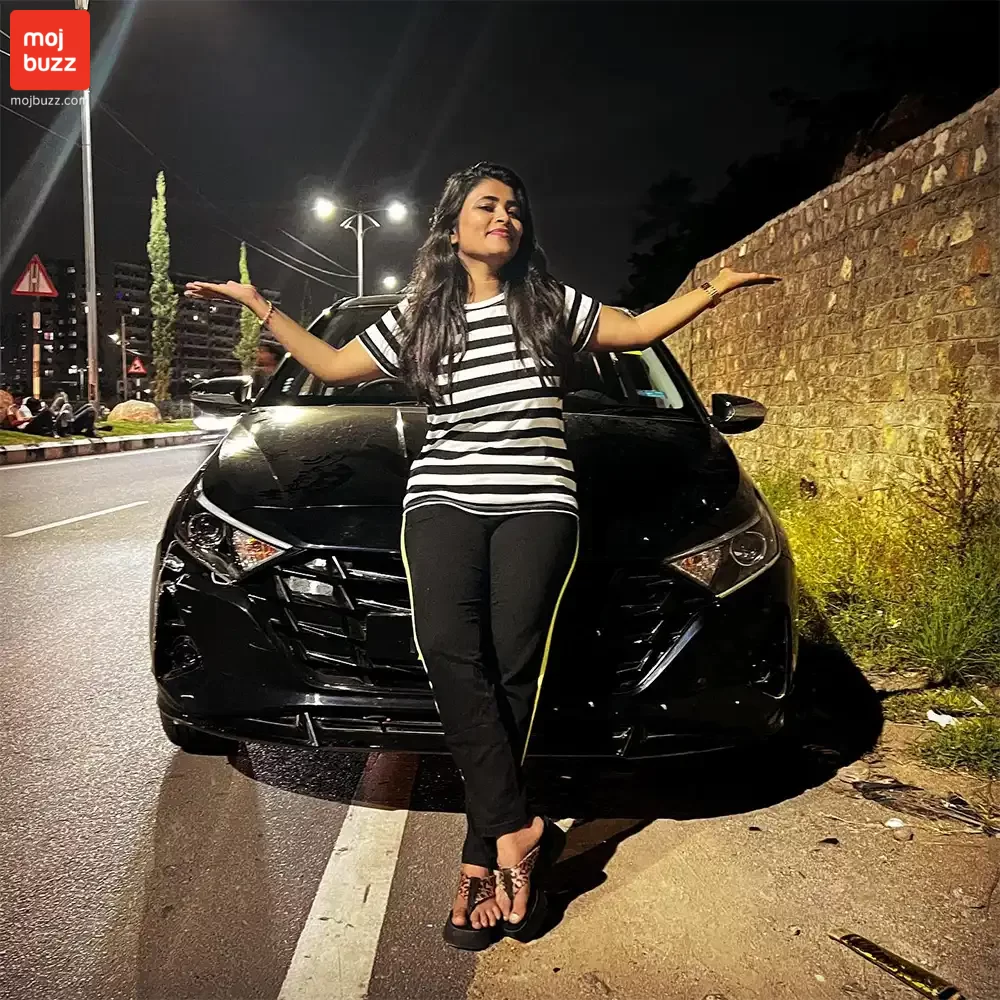 A girl (Geetu Royal) posing in front of a black car