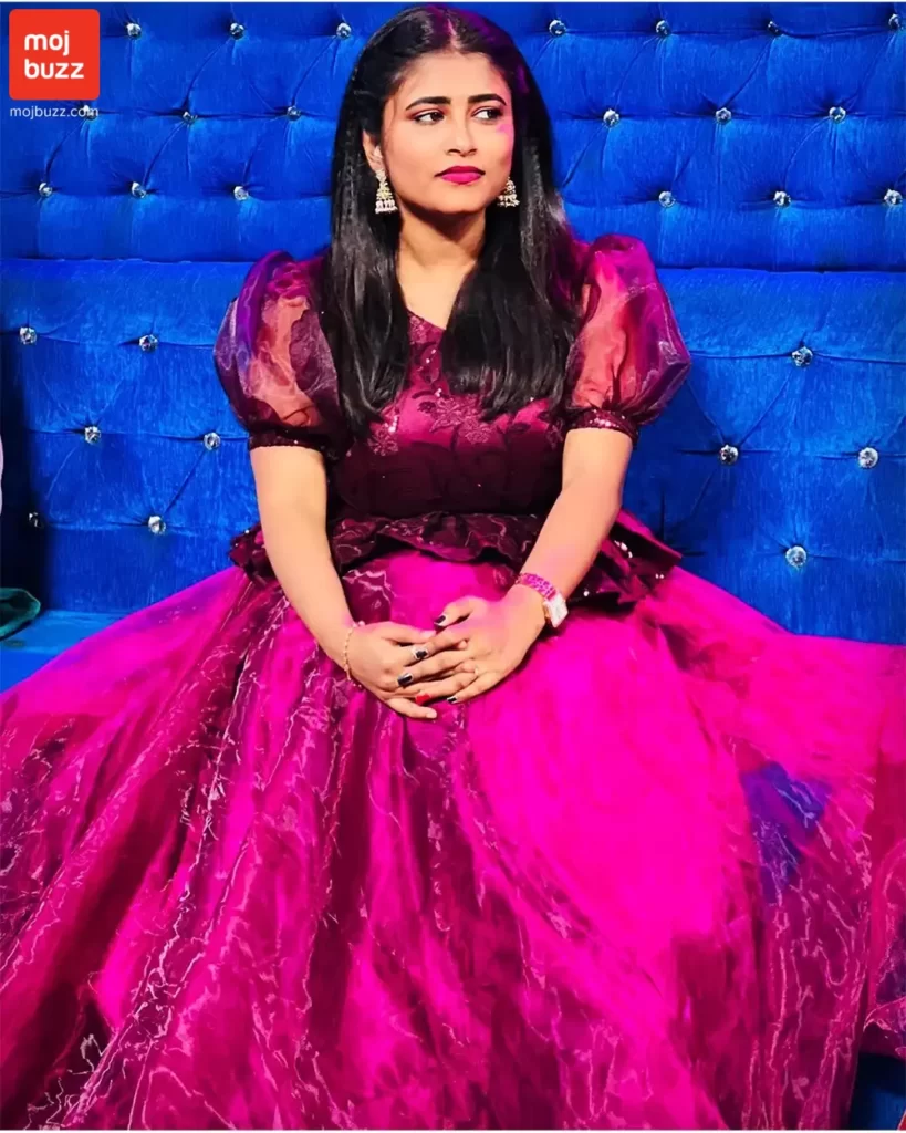 A girl (Geetu Royal) wearing a pink dress seating on a blue sofa