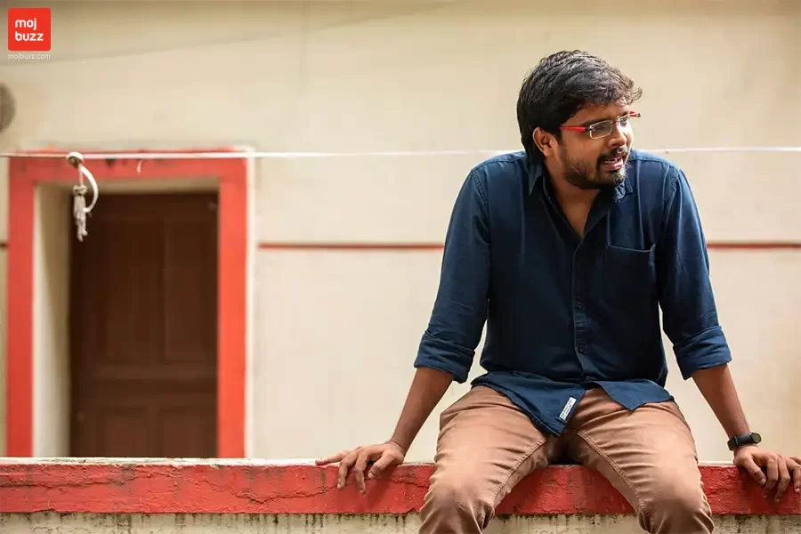 A man in blue shirt seating on roof top wall