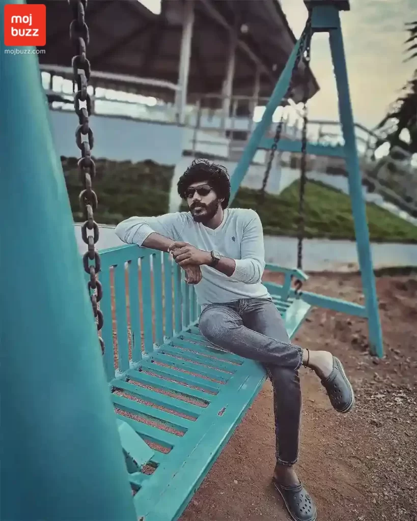 A man (Rj Surya) wearing blue t-shirt seating on a swing