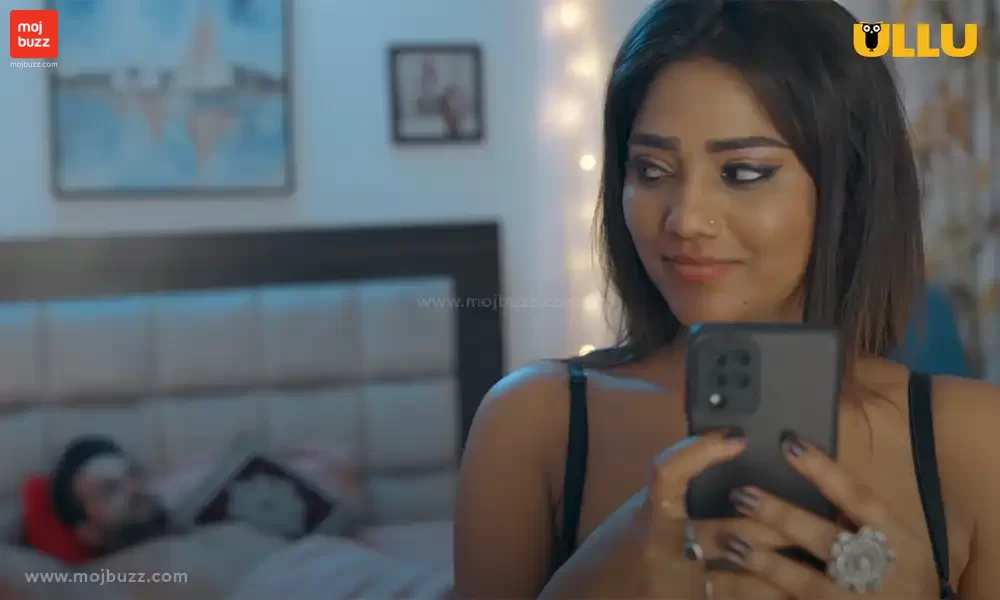 A man is lying on bed and a girl texting someone and smiling standing in front of bed in Samne wali khidki web series