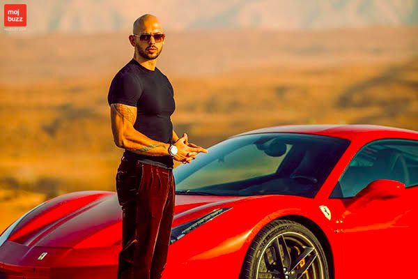 Andrew Tate standing in front of Red Farrari car that he owns